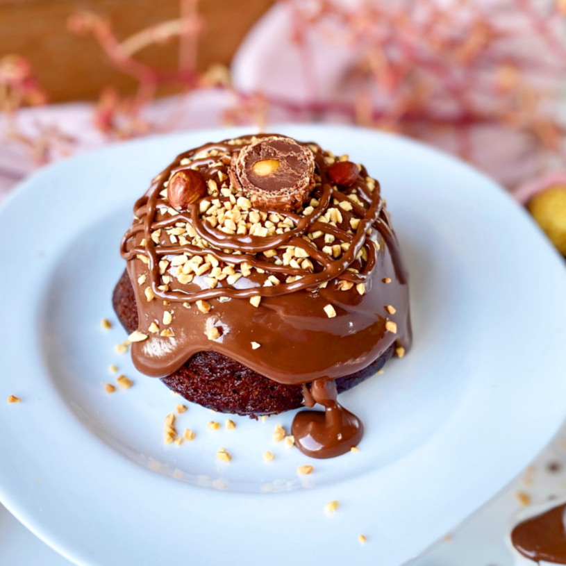 O Bolo Vulcão Ferrero Rocher apresenta uma massa macia e saborosa de chocolate, recheada com um creme aveludado de avelãs, que transborda no primeiro corte, lembrando a erupção de um vulcão. Coberto com uma generosa camada de brigadeiro de chocolate e decorado com bombom Ferrero Rocher, amendoim e fios de Nutella. É a escolha perfeita para impressionar em qualquer ocasião especial. Ficou com agua na boca? Peca o seu e não passe essa vontade! Serve até 2 pessoas. Pesa aproximadamente 450g.