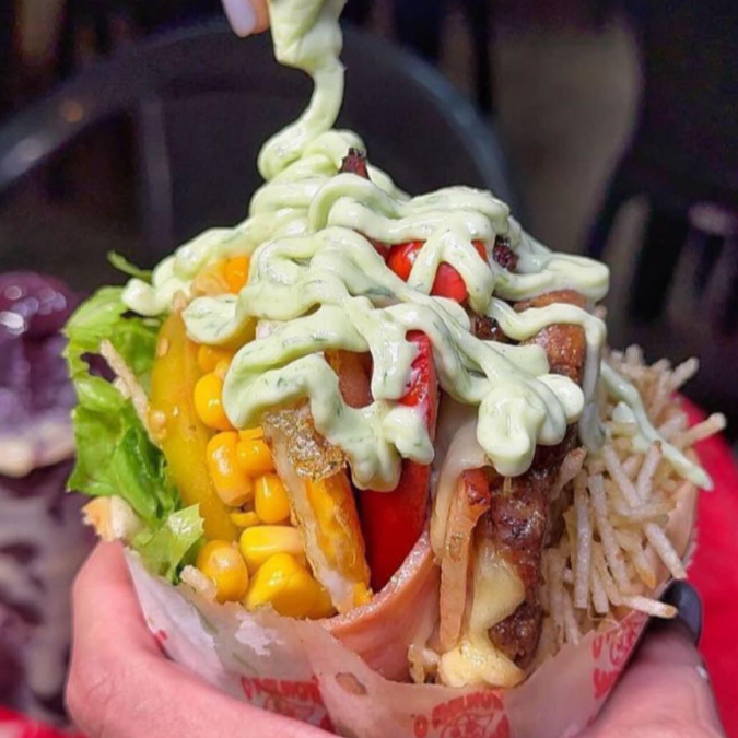 Aproveite uma combinação irresistível de muçarela, presunto, salsicha, bacon, ovo, alface, tomate, batata palha e milho, sanduiche da Pit Dog Tradicional Goiano!