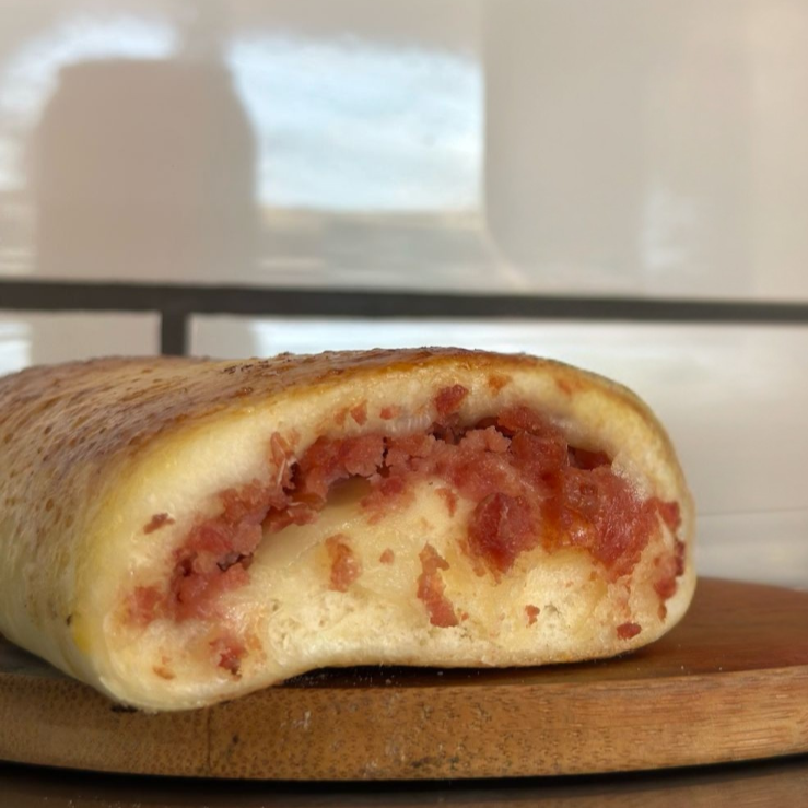 Recheio suculento de calabresa artesanal, cebola refogada e toque cremoso de cream cheese, envolto em massa fofinha e assada até o ponto perfeito.