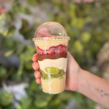 Copo composto por brigadeiro branco, uva verde, mousse de ninho, nutella, morangos frescos, finalizado com brigadeiro branco