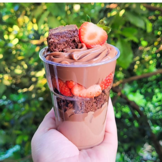 Uma explosão de sabor em cada camada! Brownie molhadinho e suculento, pedaços de morangos frescos e creme de chocolate irresistível se unem em uma combinação perfeita. Finalizado com granulê crocante e um morango fresco no topo para aquele toque especial de frescor e elegância. Um verdadeiro deleite para os amantes de chocolate!