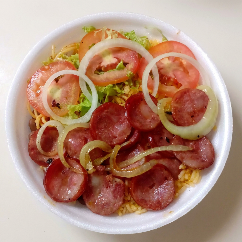 Calabresa em rodelas puxado com cebola refogada, arroz primavera, feijão mulato, macarrão ao alho e óleo, salada, farofa.