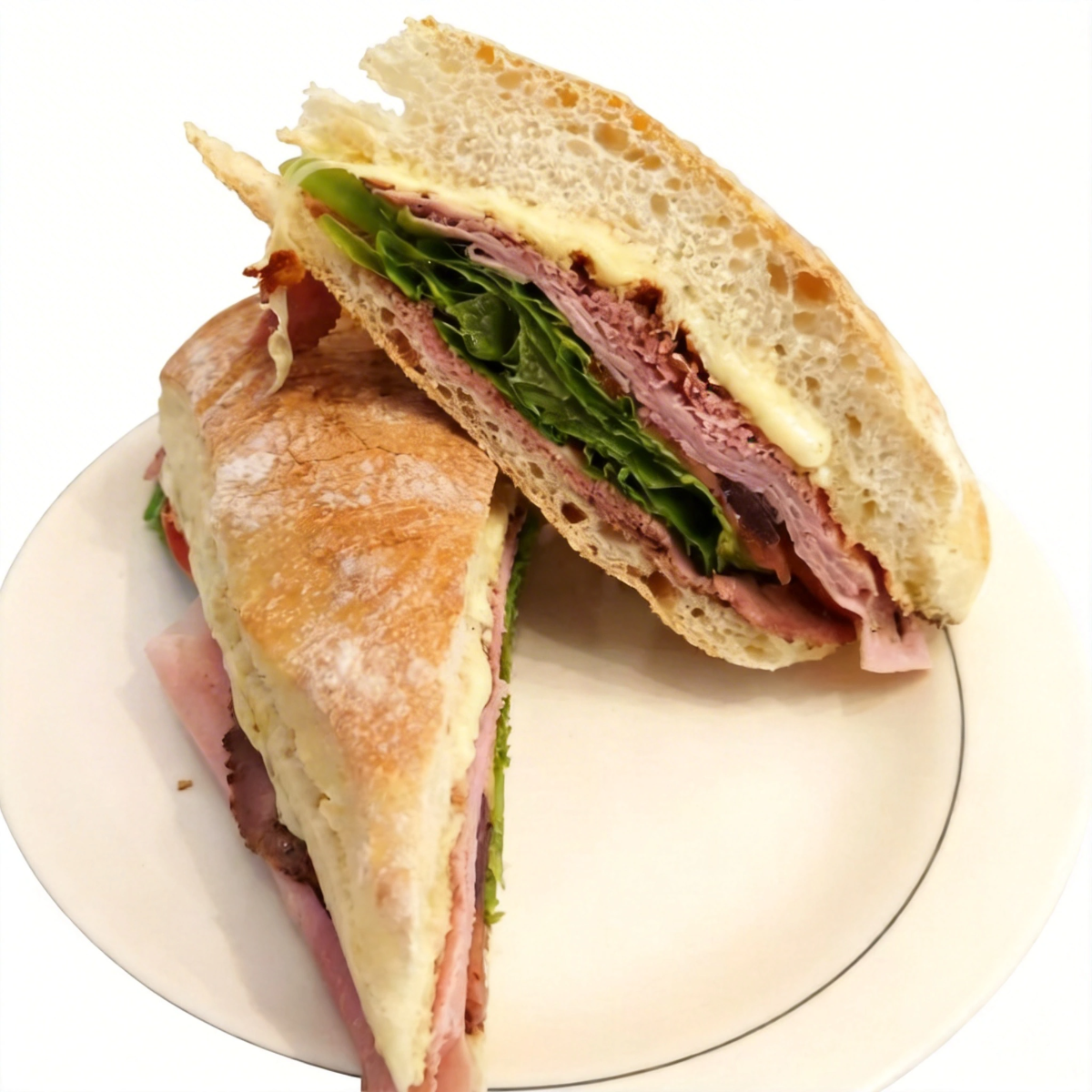 Finas fatias de roast beef artesanal, acompanhadas de presunto, queijo prato derretido, alface crocante, tomate fresco e azeitonas pretas. Uma combinação rica, suculenta e cheia de sabor em cada mordida.