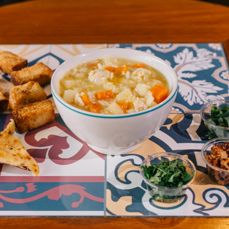 A Sopa de Canja é uma emblemática e tradicional iguaria brasileira, estrelada pelo suculento frango como protagonista. Apresenta-se em uma tonalidade clara, puxando para o amarelo, encantando os olhos antes mesmo de ser degustada. Sua textura líquida e suave proporciona um deleite ao paladar, enquanto seu sabor leve e reconfortante aquece o coração. O aroma de frango cozido mesclado às especiarias perfuma o ambiente, convidando a um momento de prazer gastronômico. Na composição, encontramos cubos de peito de frango, cebola, alho, um toque de óleo, sal na medida certa, arroz, caldo de galinha, batata e cenoura. Além de deliciosa, é uma fonte rica de proteínas e vitaminas A, B e C, com baixo teor calórico, perfeita para quem busca uma alimentação balanceada. A Sopa de Canja também fortalece o sistema imunológico, tornando-se uma opção saborosa e saudável.