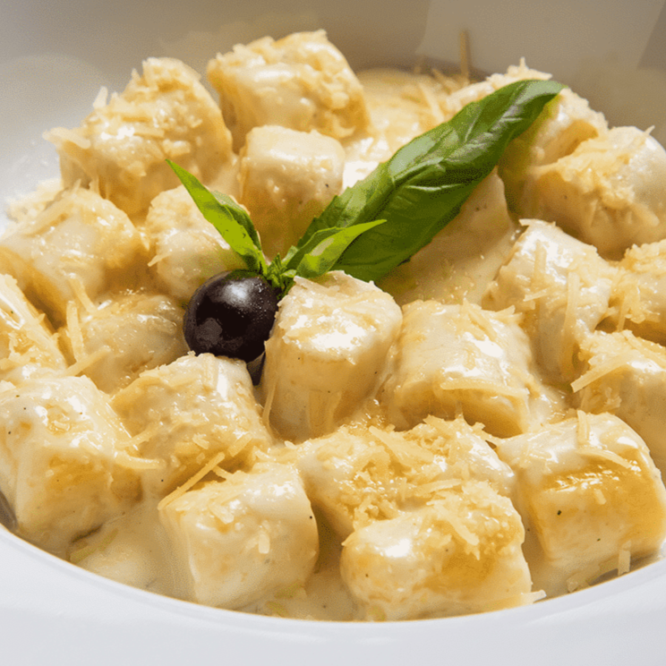 Nhoque Artesanal de Batatas, massa leve que desmancha na boca, acrescido de molho Quatro Queijos, e queijo parmesão à parte.