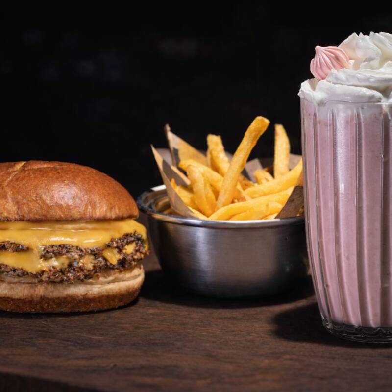 01 Hambúrguer Boom Bacon: Pão especial selado na manteiga, Burger bovino 160g, Creme cheddar (feito na casa), Tomate, Bacon Artesanal, Maionese defumada de ervas (feita na casa), geleia de cebola caramelizada. 1 Batata P (100g), quentinha, crocante e sequinha. 1 Sobremesa, escolha sua favorita!