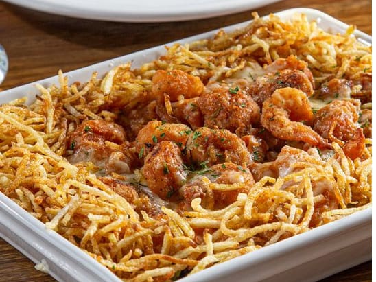 Arroz à grega (ervilhas, pimentões, passas, cenoura e presunto) coberto com camarões à milanesa, molho caseiro de tomate fresco. Gratinado com queijo mussarela. Acompanha batata palha.tamanho do camarão nesse prato: 18 g