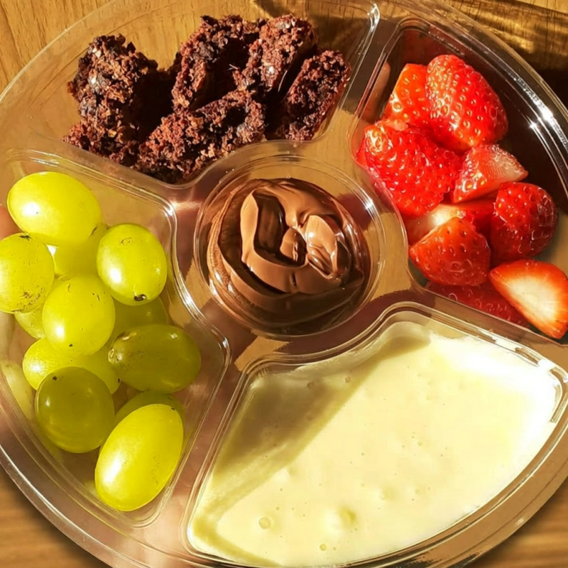 Delicioso Fondue de brownie com frutas; pedaços de browie macios, brigadeiro, creme de avelã, morangos frescos, uvas verde sem caroço. Compartilhe esse momento! Serve até 2 pessoas.
