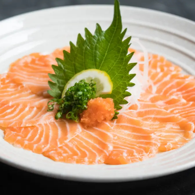 Fatias finas de salmão com molho cítrico e cebolinha.
