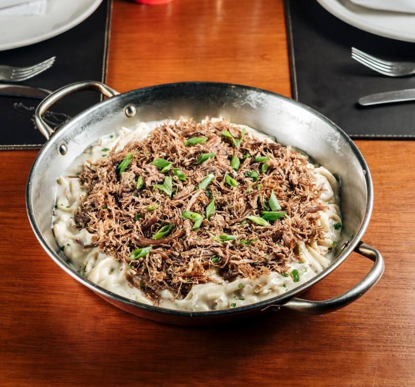 Carne de Sol desfiada grelhada sobre fettuccine com molho alfredo e bacon.