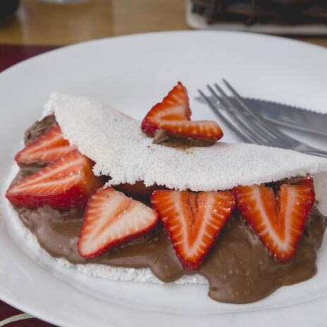 Tapioca macia e leve, recheada com creme de chocolate e avelã, acompanhada de morangos fresquinhos.