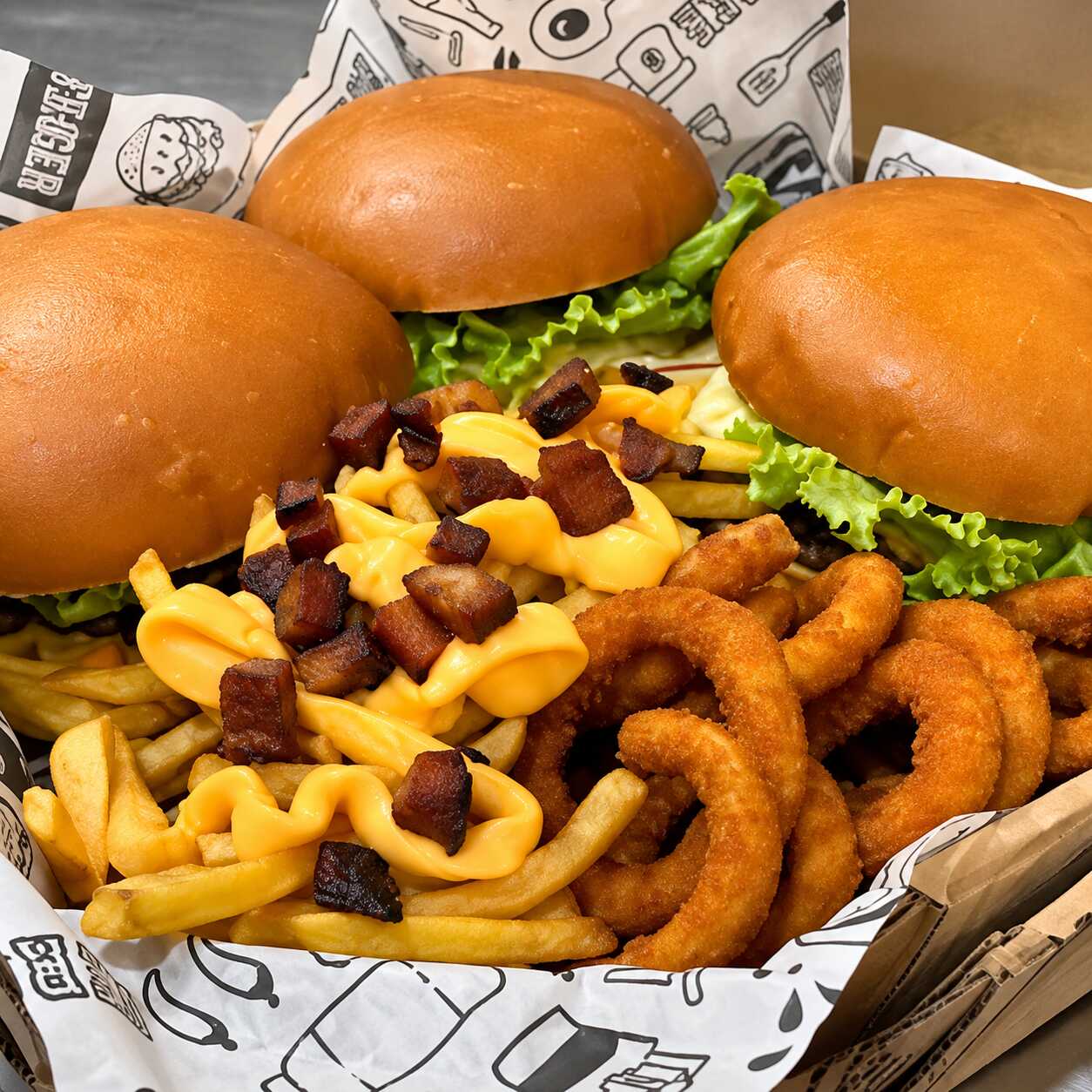 3 Burguer Salada (pão brioche, hambúrguer, bacon, cheddar, alface e tomate), acompanhados de anéis de cebola e Batata Turbinada. Um pedido farto, variado e ideal para a família.