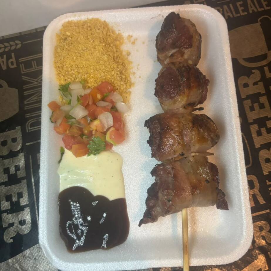 Delicioso espetinho de carne com bacon, preparado na brasa para ficar douradinho, suculento e cheio de sabor, combinando a maciez da carne com aquele toque irresistível do bacon! Acompanha 4 acompanhamentos à sua escolha entre nossas opções: farofa, vinagrete, molho barbecue e creme de alho. Você escolhe seus favoritos e monta seu prato do seu jeito!