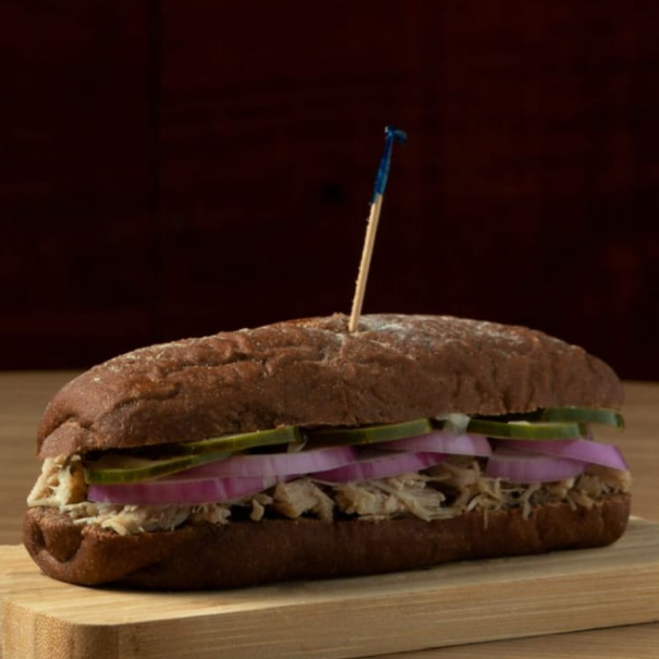 Sanduíche no pão artesanal com pernil desfiado, cebola roxa, picles da casa e barbecue