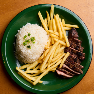 Corte suculento de Alcatra, grelhada no ponto certo para realçar todo o sabor da carne. Ideal para quem ama uma refeição saborosa e bem temperada! Acompanha: Arroz branco, farofa de bacon, batata-frita e feijão preto.Aproximadamente 500g.