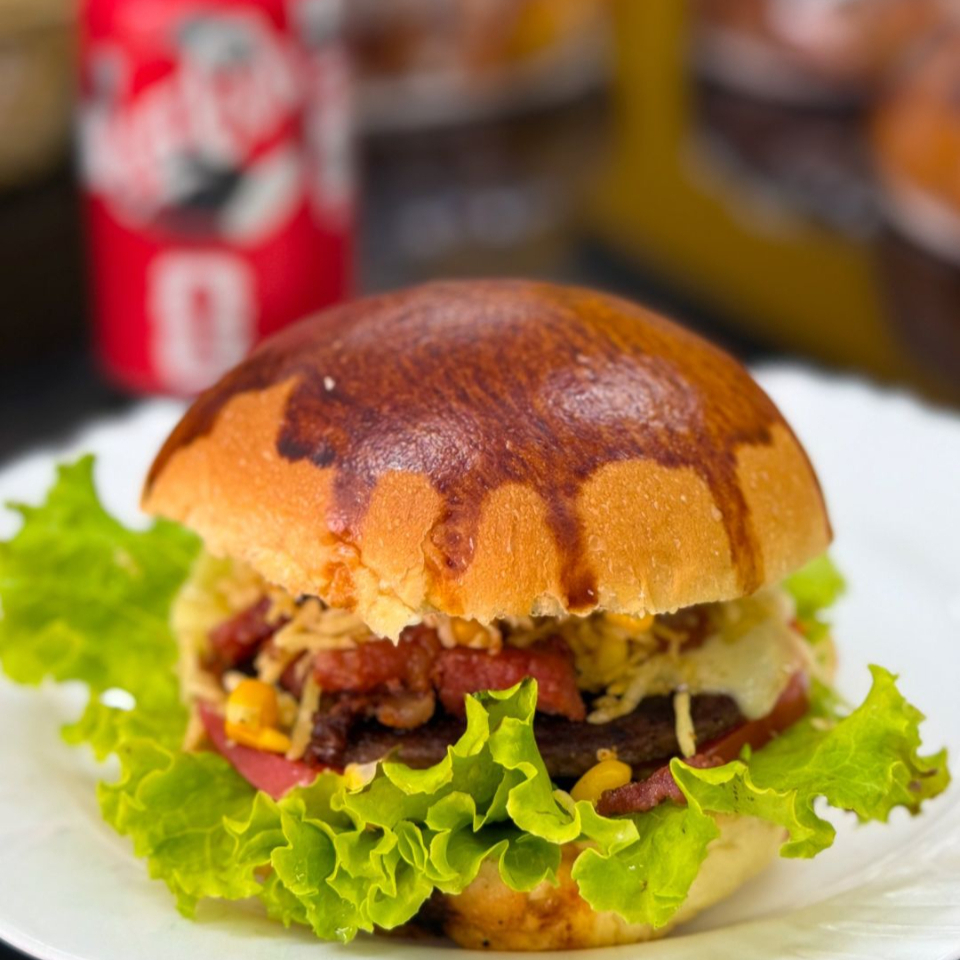 Hambúrguer suculento com bacon crocante, muçarela derretida, maionese, milho, alface, tomate e batata palha. Sabor marcante em cada mordida
