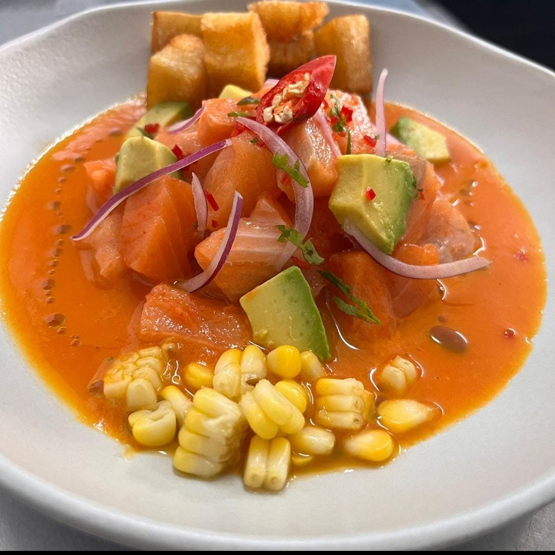 Cubos de salmão com leite de tigre de pimenta amarela, cebola roxa, mandioca crocante, milho verde, abacate e óleo de coentro.