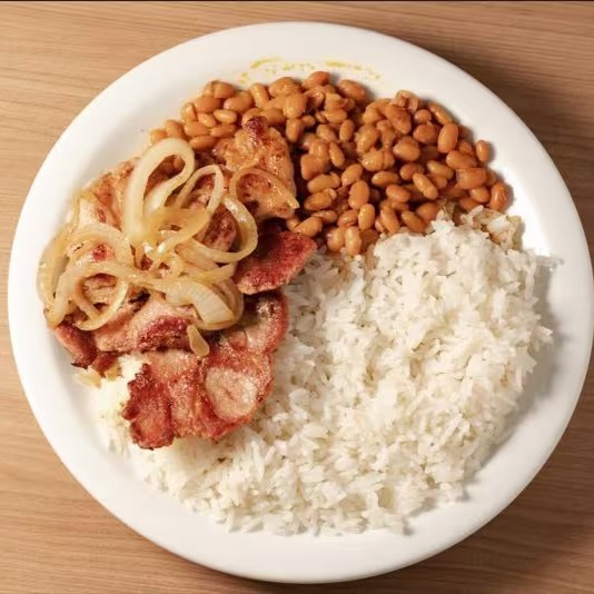 Delicie-se com o nosso Bife Suíno, cuidadosamente selecionado e perfeitamente grelhado para atingir uma suculência inigualável. Este prato é harmoniosamente acompanhado de arroz cuidadosamente cozido e feijão, ambos preparados seguindo as tradições culinárias brasileira.