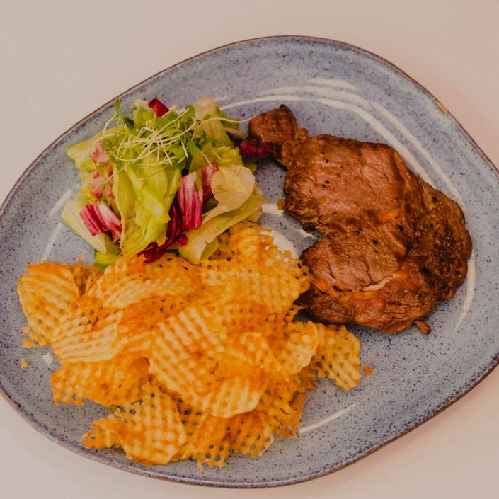Filé alto de bife ancho, acompanhado por batatas crocantes e molho amanteigado da casa .