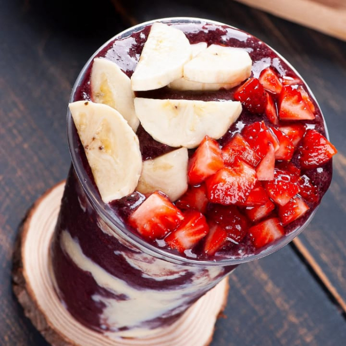 copo de 400ML com açai acompanhado de leite condensado leite em pó com as frutas banana e morango