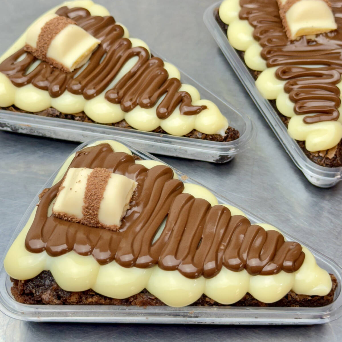 Fatia de pizza brownie chocolatuda muito recheada com brigadeiro ninho, nutella e kinder bueno. Peça agora mesmo a sua! Peso médio de 140g.