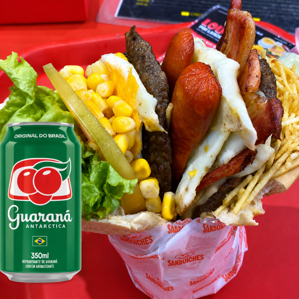 Hambúrguer Completo com Bacon, Salsicha, Ovo, Presunto, Mussarela, Tomate, Alface, Milho e Batata Palha. Acompanha Guaraná Antarctica 350ml pra Combinação Perfeita!