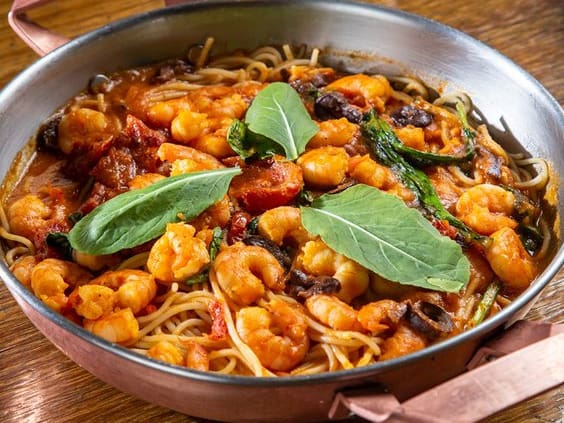 Espaguete italiano coberto com delicioso molho de tomate fresco acrescido de tomate seco, azeitona, rúcula e camarões. tamanho do camarão nesse prato: 13g.