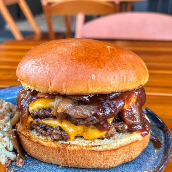 Pão de Brioche tostado na manteiga, 240g hambúrguer artesanal (120g cada), duplo queijo cheddar fatia, bacon premium crocante, Barbecue, deliciosa cebola caramelizada. Cortesia da Casa: Batata Rustica e a Super Maionese Temperada que é de tirar o folego.