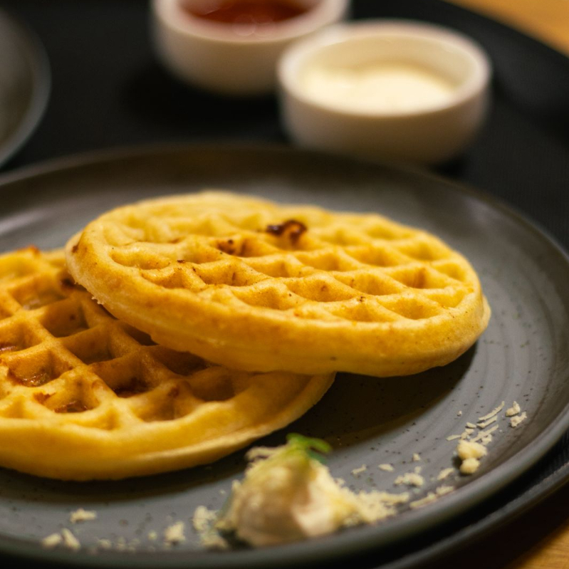 Waffles com massa de pão de queijo. Acompanham geleia de frutas vermelhas da casa e cream cheese.