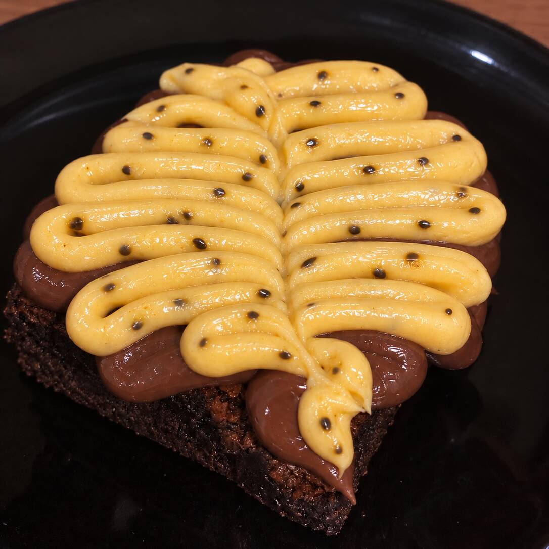 Descrição: Brownie de chocolate com brigadeiro cremoso e brigadeiro de maracujá.(Aprox 150g)