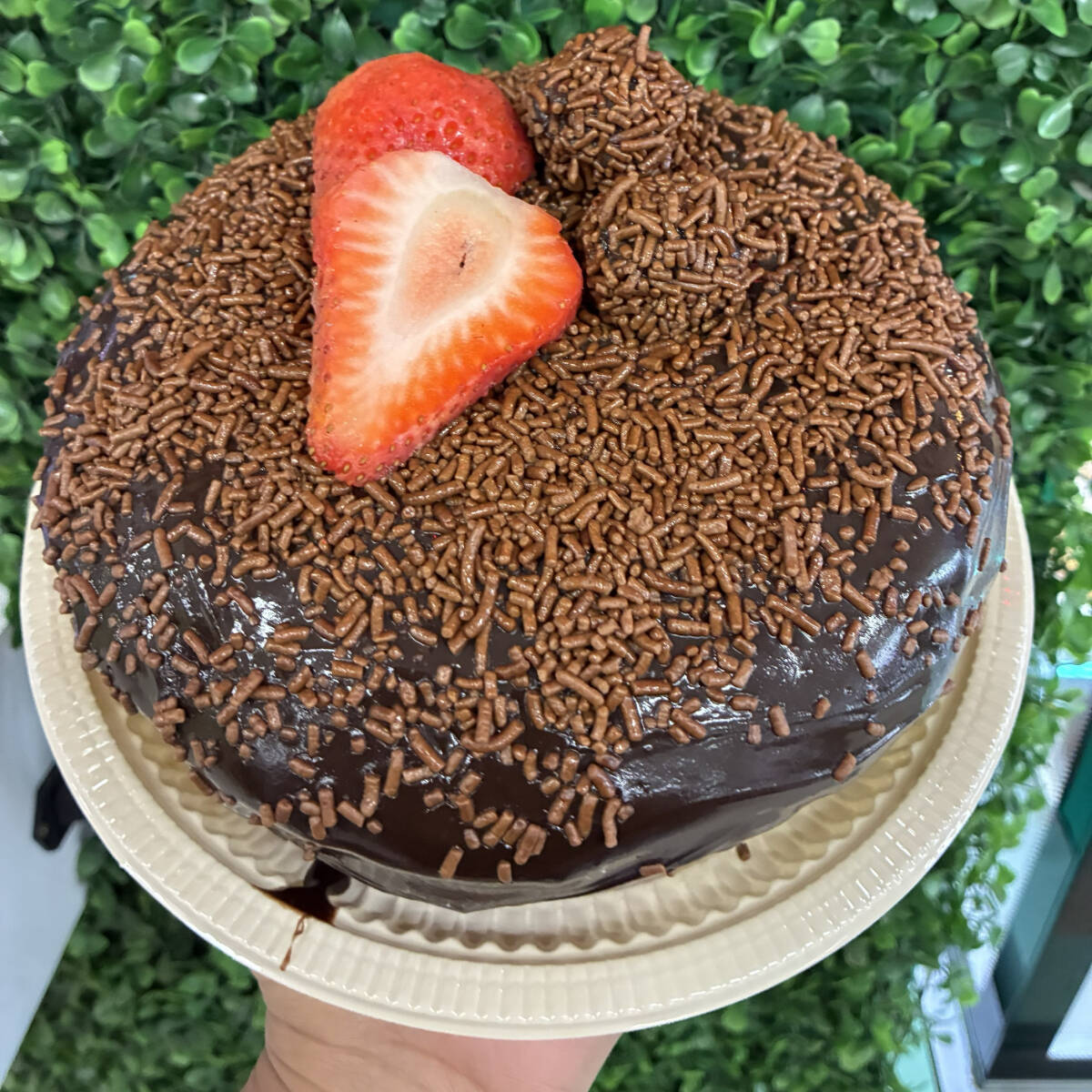 Massa: chocolate Recheio/Calda: calda de brigadeiro Cobertura/Decoração: barra de chocolate ao leite ralada e com 2 morangos decorando.