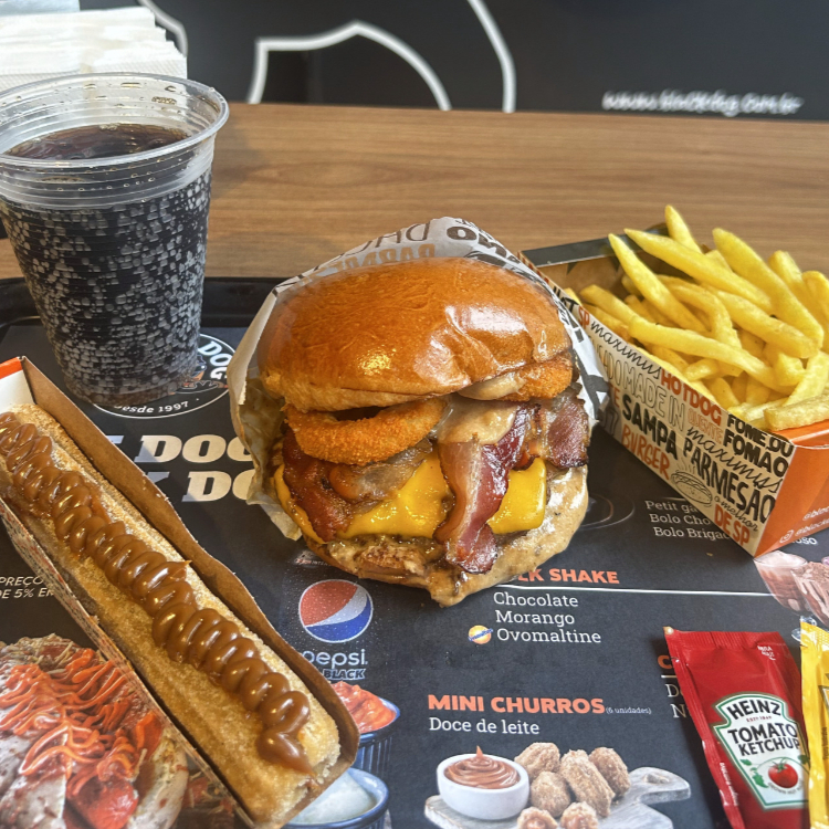Pão de Hambúrguer com ou sem gergelim, Molho defumado, hamburguer feito com blend de carnes angus 160g, queijo tipo cheddar fatiado, onion rings e bacon. + Churros de Doce de leite + Refri lata geladinho à sua escolha.