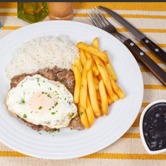 Bife suculento preparado na chapa no ponto certo, mantendo maciez e sabor, finalizado com ovos fritos na medida ideal, trazendo equilíbrio entre proteína e textura. Um prato clássico, bem servido, feito com ingredientes frescos e preparo cuidadoso, acompanhado de arroz soltinho, feijão caseiro, farofa crocante e salada fresca.