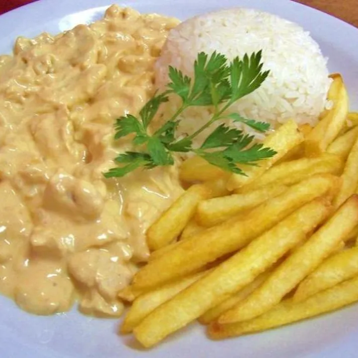 Strogonoff de frango cremoso e bem temperado, acompanhado de arroz branco soltinho e fritas. Uma combinação clássica, completa e cheia de sabor para o seu almoço.