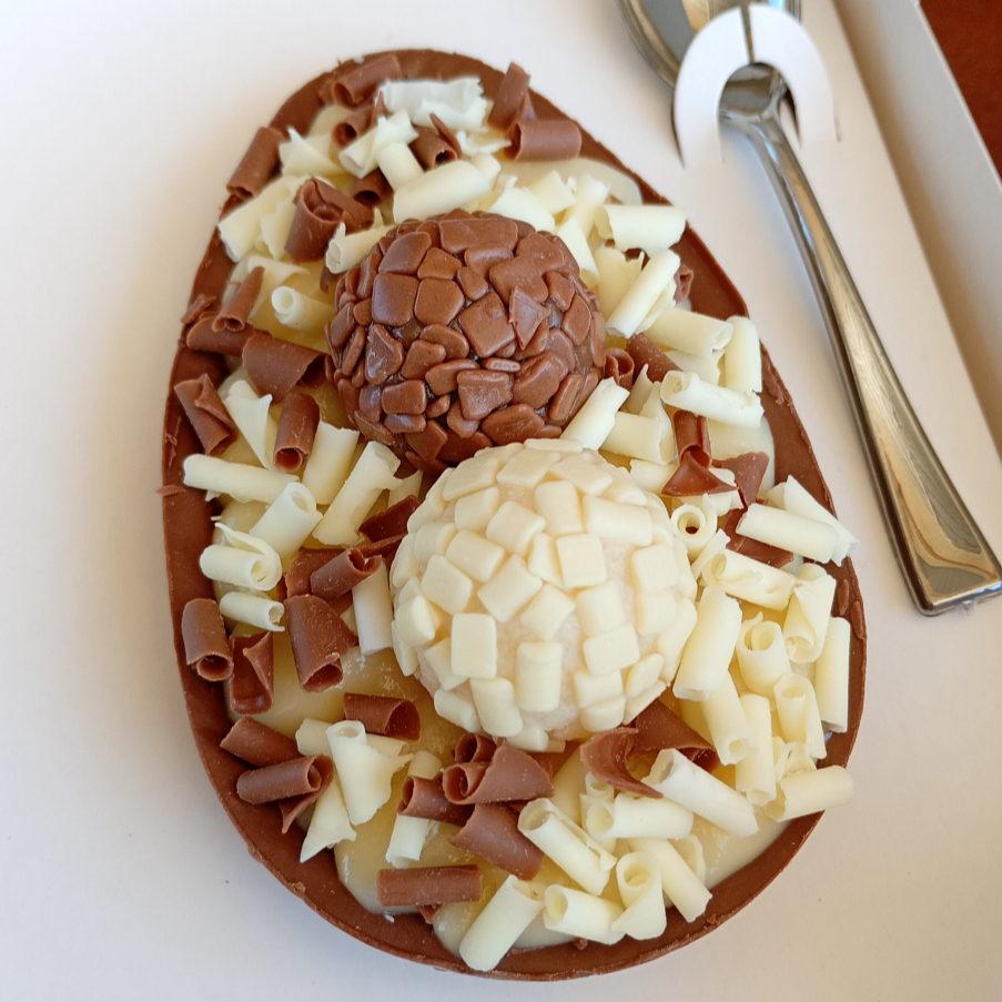 Delicie-se com esse maravilhoso ovo de colher, preparado com casca de chocolate nobre, duplamente recheado com nosso delicioso brigadeiro gourmet ao leite, coberto por outra camada do nosso brigadeiro de ninho, decorado com lascas de chocolate belga branco calebaut, e brigadeiro ao leite belga, finalizado com brigadeiro gourmet e brigadeiro de ninho.