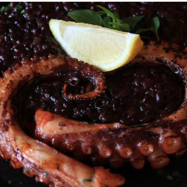 Suculento Polvo grelhado na parrilla com brasa de laranjeira, com acompanhamento de risoto Nero trufado