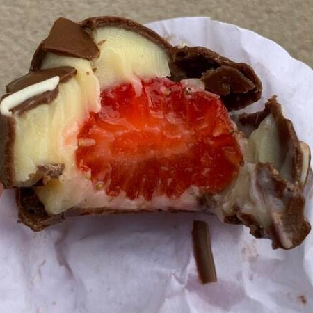 Morango fresco, envolvido no brigadeiro de leite ninho, banhado no chocolate bland.