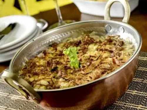 Arroz de leite coberto com carne de sol desfiada e refogada na manteiga da terra com cebola roxa, nata e coentro. Gratinada com queijo coalho. Acompanha macaxeira frita.