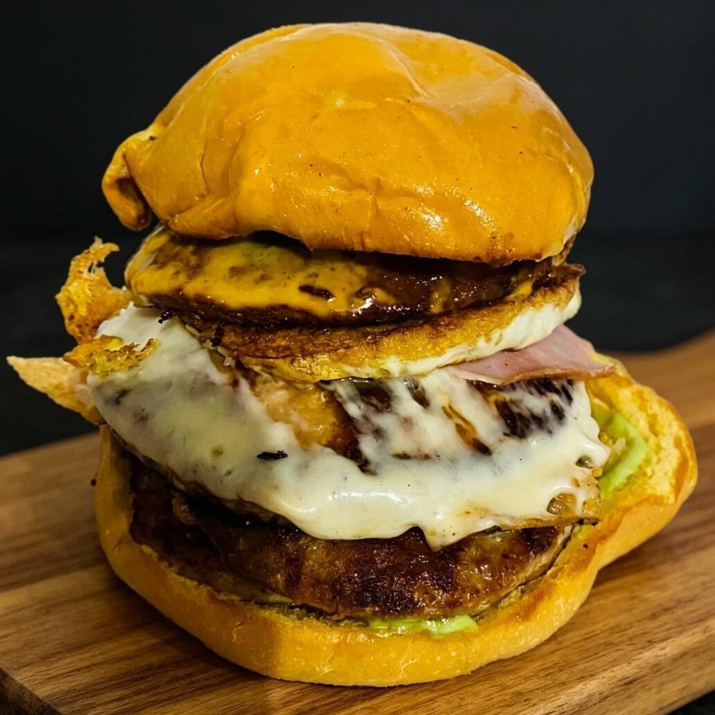 PÃO TRADICIONAL, 4X CARNE INDUSTRIAL, OVO, PRESUNTO, MUSSARELA, MOLHO CHEDDAR, KETCHP E MAIONESE DEFUMADA DA CASA.