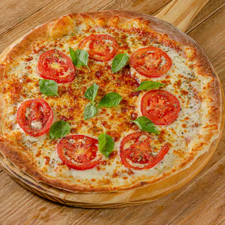 Massa da casa, banhada ao nosso delicioso molho de tomate. Sobre o molho, uma base generosa de queijo muçarela, combinando perfeitamente com cortes finos de tomate e uma porção suave de folhas de manjericão. E para finalizar, uma pitada de orégano sobre a pizza.