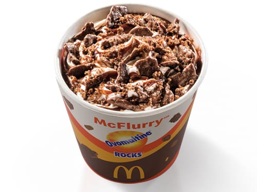 Bebida láctea sabor baunilha, cobertura sabor chocolate, Ovomaltine em pó e pedaços crocantes de Ovomaltine Rocks