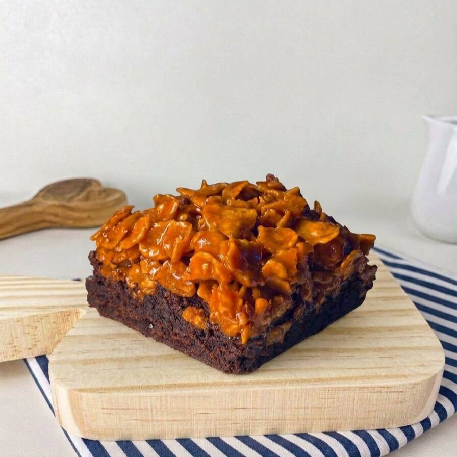 Nosso brownie intenso e extremamente macio ganha uma camada irresistível de crocante de sucrilhos caramelizados, criando o contraste perfeito entre cremosidade e crocância. Um doce cheio de personalidade, com textura, sabor e presença em cada mordida. Daqueles que surpreendem do primeiro ao último pedaço.