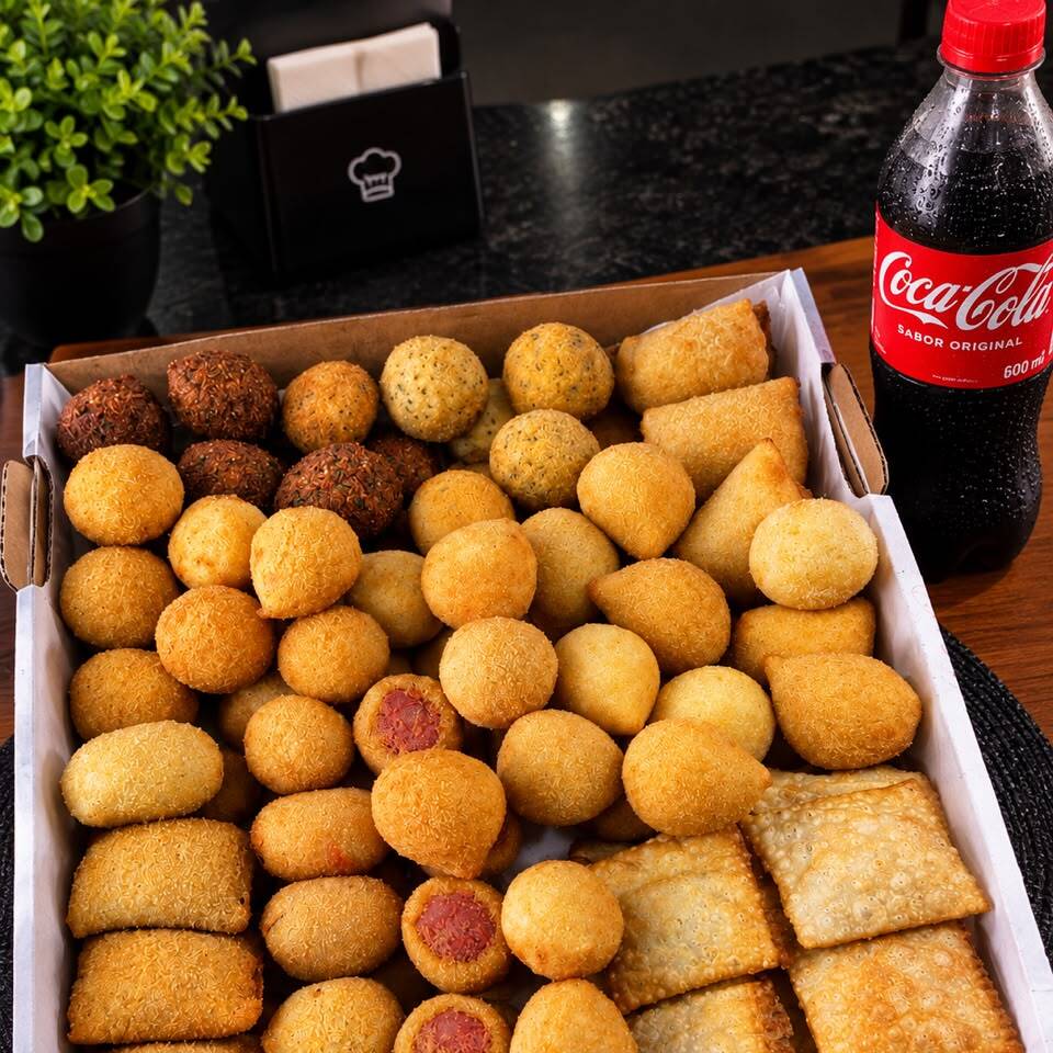 50 mini salgados variados (crocantes e sequinhos) + 1 Refrigerante bem gelado. Fartura e sabor na medida certa para o seu lanche.