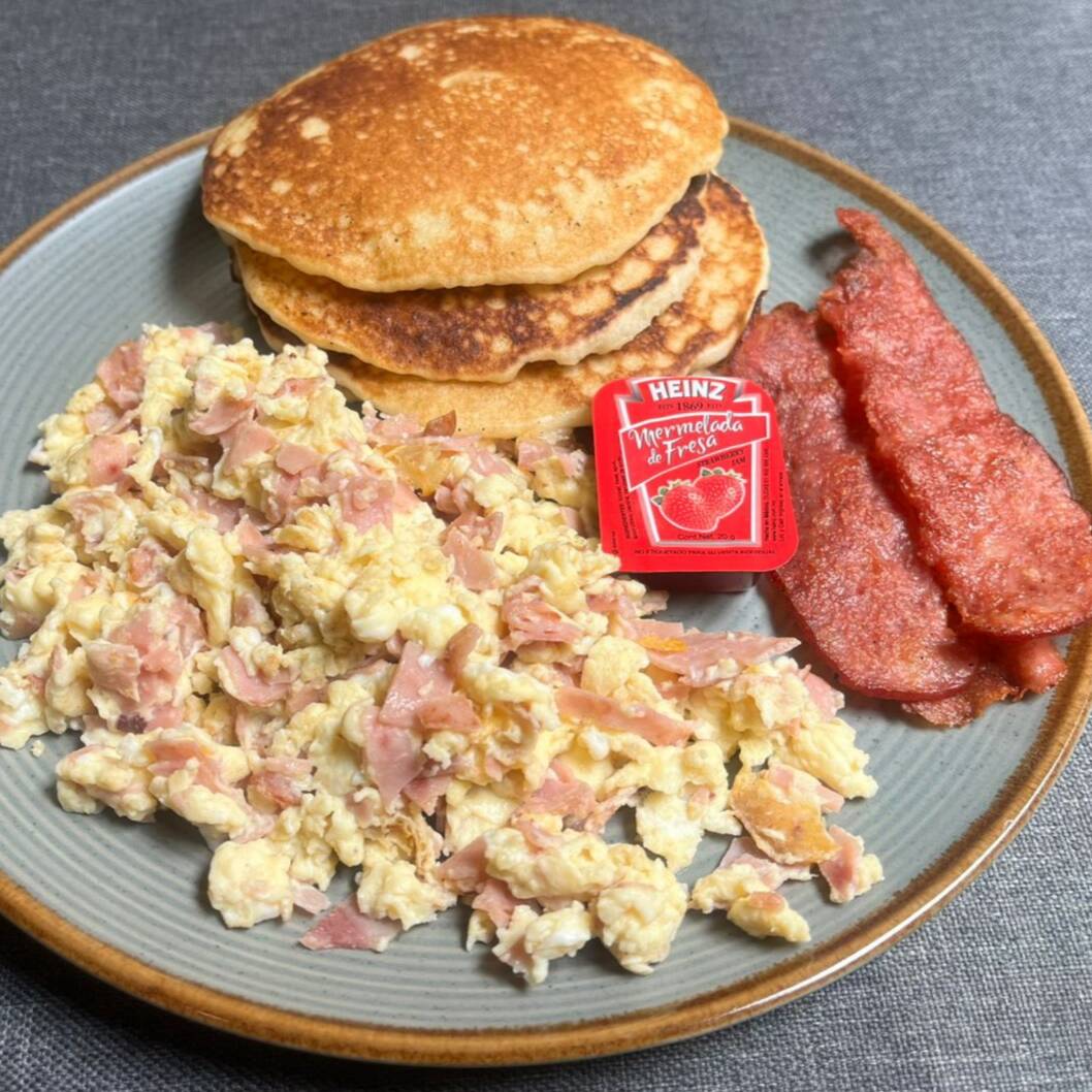 Huevos al Gusto acompañados de hot cakes y tocino