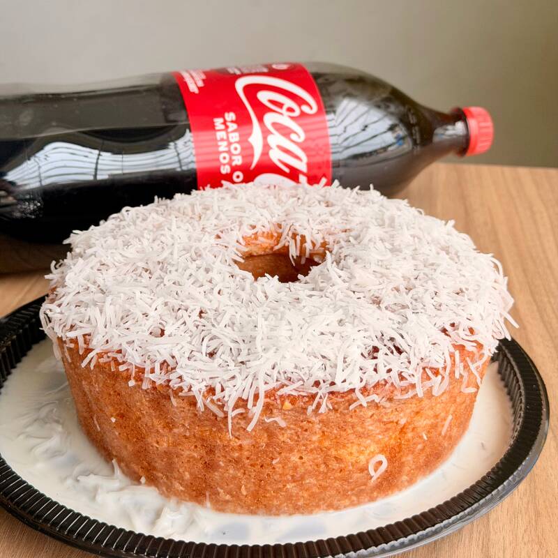 Bolo caseiro de massa bem molhadinha coberto com coco. Acompanhado com uma Coca-Cola de 2 litros gelada