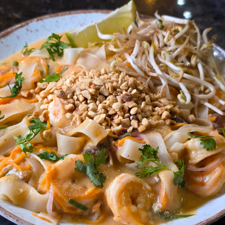 O Pad Thai é um prato clássico tailandês de macarrão de arroz frito no wok, conhecido pelo equilíbrio agridoce e salgado. Leva macarrão, ovos, tofu, camarão, broto de feijão, amendoim e um molho característico de tamarindo e peixe. É servido com limão, finalizando com sabores frescos e texturas crocantes.