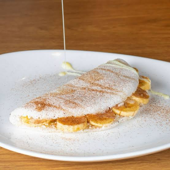 Uma combinação clássica que aquece o coração! Tapioca preparada na hora, recheada com banana fresquinha, leite condensado cremoso e um toque especial de canela, criando um sabor irresistível, aromático e cheio de carinho em cada mordida. Uma verdadeira sobremesa nordestina que encanta do início ao fim.