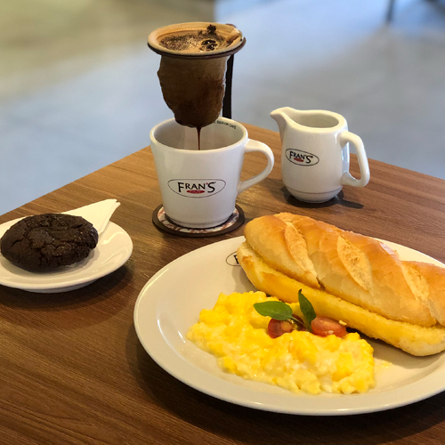 1 Café Coado ou Filtrado Grande • 1 Fran's Baguete Tostada com Manteiga • 1 porção de Ovos Mexidos • 1 Cookie