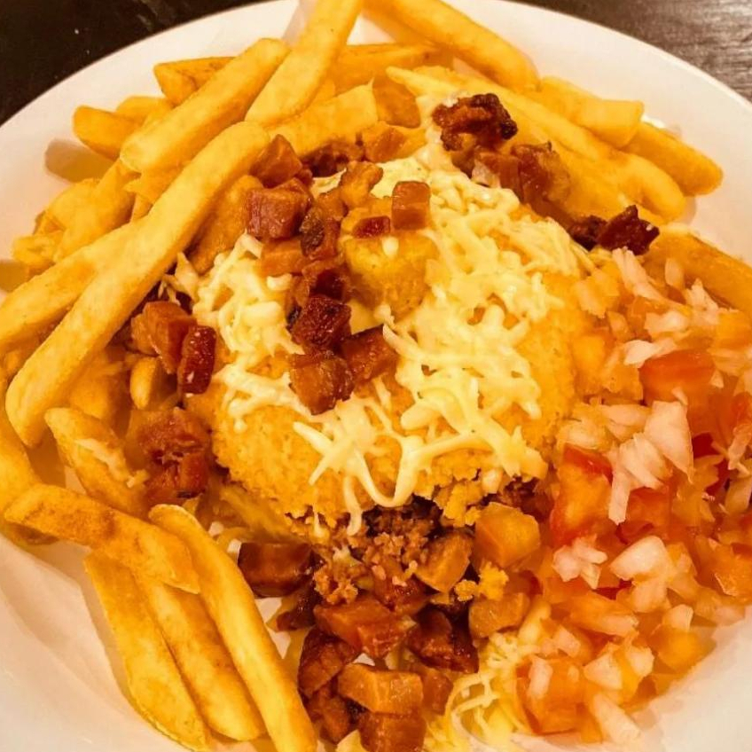 Cuscuz recheado com carne seca, coberto com mussarela derretida, acompanha vinagrete, bacon e batata frita