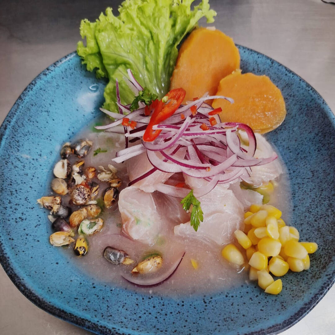 Cortes de peixe branco marinados com leite de tigre e servidos com batata doce, cebola roxa, alface, milho verde e milho peruano